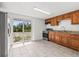 Compact kitchen features tile flooring, wooden cabinetry, stainless-steel appliances, and sliding door access to backyard at 2305 N 48Th St, Tampa, FL 33605