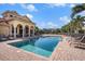 Stunning community pool area with ample lounge seating, a beautiful building facade, and lush palm trees at 2515 63Rd Ter E, Ellenton, FL 34222