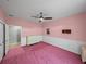 Pink bedroom featuring a ceiling fan, pink carpet, and white wainscoting at 30017 Johnston Rd, Dade City, FL 33523