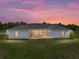 Sunset view of the rear exterior showcasing the brick patio and string lights at 30017 Johnston Rd, Dade City, FL 33523