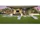 Outdoor lounge area with a large fireplace, TV, comfortable seating, and a cornhole game on the turf at 34053 Anchor Light Ln, Wesley Chapel, FL 33543