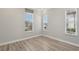 Bright bedroom featuring wood flooring, three windows, and neutral color palette at 4325 Barletta Ct, Wesley Chapel, FL 33543
