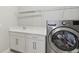 Laundry room with sink, cabinets, shelf, and stainless steel washing machine at 4325 Barletta Ct, Wesley Chapel, FL 33543