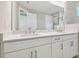 Bright bathroom featuring a double sink vanity, a large mirror, and white cabinets at 4709 Isonzo Way, Wesley Chapel, FL 33543