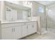 Modern bathroom featuring double sinks, sleek white cabinetry, and a walk-in shower with light tile at 4709 Isonzo Way, Wesley Chapel, FL 33543