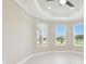 Bright bedroom featuring a ceiling fan and three windows providing lots of natural light and outdoor views at 4709 Isonzo Way, Wesley Chapel, FL 33543
