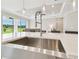 Bright kitchen featuring a stainless steel sink, modern faucet, and an island that overlooks the living area at 4709 Isonzo Way, Wesley Chapel, FL 33543