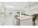 Open-concept kitchen with a large island, stainless steel sink, white cabinetry and views of the outdoors at 4709 Isonzo Way, Wesley Chapel, FL 33543