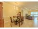 Open dining room with glass table set that opens to a spacious living room with a lake view at 4821 Grand Banks Dr, Wimauma, FL 33598