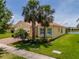 Charming yellow home with palm trees and bay window, showcasing curb appeal at 4821 Grand Banks Dr, Wimauma, FL 33598