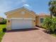 A yellow home with a white garage door and brick driveway offers a neat exterior at 4821 Grand Banks Dr, Wimauma, FL 33598