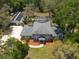 An aerial view of a two-story home with a pool, screened enclosure, lush landscaping and detached garage at 5305 Lenoir Ct, Plant City, FL 33566