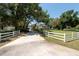 Inviting view of a home down a long driveway, framed by a white fence and mature trees, showcasing curb appeal at 5305 Lenoir Ct, Plant City, FL 33566