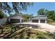 Spacious detached three-car garage and driveway with mature landscaping and a partially fenced yard at 5305 Lenoir Ct, Plant City, FL 33566