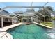 Screened in-ground pool with lush landscaping, waterfall feature, brick patio and outdoor kitchen at 5305 Lenoir Ct, Plant City, FL 33566