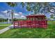 Picturesque red gazebo overlooking a scenic lake with a fountain, surrounded by lush greenery at 5480 Orange Blossom N Rd, Pinellas Park, FL 33782