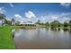 Beautiful lake view featuring a well-maintained building, palm trees, and green grass shoreline at 5480 Orange Blossom N Rd, Pinellas Park, FL 33782