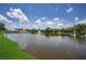 Scenic lake view featuring a fountain, lush green grass, and a glimpse of a charming building in the background at 5480 Orange Blossom N Rd, Pinellas Park, FL 33782