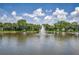 Calm lake view showcasing a central water fountain, surrounded by lush greenery and palm trees at 5480 Orange Blossom N Rd, Pinellas Park, FL 33782