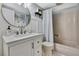 Bathroom features white wainscoting, a modern vanity, round mirror, and tub shower combo at 550 George S St, Tarpon Springs, FL 34688