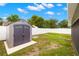 Backyard view featuring a storage shed, green lawn, and white fence at 6433 Reef Cir, Tampa, FL 33625