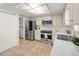Well-lit kitchen featuring stainless steel appliances, white cabinets, and neutral-colored tile flooring at 6433 Reef Cir, Tampa, FL 33625