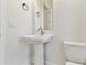 Powder bathroom featuring a pedestal sink, toilet and stylish black and white tile flooring at 7304 Donnybrook Ln, Sarasota, FL 34240