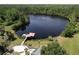 Aerial view of a tranquil lake with a dock and recreation area nestled among lush greenery at 8016 Rock Spring Ct, Land O Lakes, FL 34638