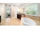 Bright bathroom with soaking tub, double vanity with dark cabinets, and tile floor at 8016 Rock Spring Ct, Land O Lakes, FL 34638