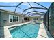 A crystal blue swimming pool in a screened in enclosure with a jacuzzi and patio furniture at 8016 Rock Spring Ct, Land O Lakes, FL 34638