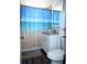 Bright bathroom featuring a toilet, sink, and shower with a blue beach-themed shower curtain at 8996 Southern Comfort Dr, Largo, FL 33773