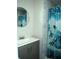 Bathroom featuring a vanity sink and shower with a blue shower curtain and neutral stone walls at 8996 Southern Comfort Dr, Largo, FL 33773