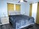 Bright bedroom featuring a bed with nightstands, curtains, a ceiling fan, and modern gray wood-look flooring at 8996 Southern Comfort Dr, Largo, FL 33773