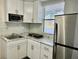 Bright kitchen featuring white cabinets, stainless steel refrigerator, and granite countertops at 8996 Southern Comfort Dr, Largo, FL 33773