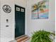 Stylish front door with green paint and palm tree art for curb appeal, complemented by lush greenery and a welcome mat at 9812 Indian Key Trl # 84, Seminole, FL 33776