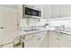 Bright kitchen area with stainless steel microwave, sleek cooktop, light countertops and white cabinets at 9812 Indian Key Trl # 84, Seminole, FL 33776