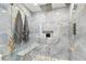 Luxurious shower with gray marble tiling, pebble floor, a built-in bench, and sleek fixtures at 9812 Indian Key Trl # 84, Seminole, FL 33776