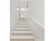 Bright staircase features light wood treads and white risers, complemented by a sleek white handrail and modern lighting at 9812 Indian Key Trl # 84, Seminole, FL 33776