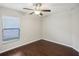 Cozy bedroom features a ceiling fan, window with blinds, and sleek hardwood floors at 10326 Boggy Moss Dr, Riverview, FL 33578