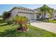 Charming single-story home with a well-manicured lawn, palm trees, and a two-car garage at 10326 Boggy Moss Dr, Riverview, FL 33578