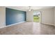 Spacious living room with a blue accent wall and sliding glass doors at 10326 Boggy Moss Dr, Riverview, FL 33578