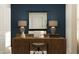 This home office features a dark blue wall, a long desk, and beige colored lamps for a contemporary style at 11746 Brae Way, Dade City, FL 33525