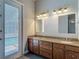Bathroom boasts double vanity with granite countertop and decorative light fixtures, next to door to exterior at 13110 Manistee Rd, Weeki Wachee, FL 34614