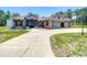 Charming single-story home with a three-car garage and circular driveway in a lush, green landscape at 13110 Manistee Rd, Weeki Wachee, FL 34614
