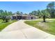 Beautiful single-story home with a three-car garage, and a long circular driveway in a lush landscape at 13110 Manistee Rd, Weeki Wachee, FL 34614