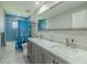 Bathroom featuring a double vanity with a marble countertop and blue tiled shower at 1503 Albemarle Ct, Dunedin, FL 34698