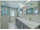 Bright bathroom with a double sink vanity, tiled shower with glass door, and backyard access at 1503 Albemarle Ct, Dunedin, FL 34698