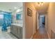 Bathroom featuring a double vanity with a marble countertop, a blue tiled shower and a hallway view at 1503 Albemarle Ct, Dunedin, FL 34698