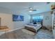 Bright bedroom with blue accent art, a ceiling fan, and a comfortable bed with wood floors at 1503 Albemarle Ct, Dunedin, FL 34698