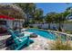 Backyard oasis featuring a pool, firepit, and lounge area with lush landscaping at 1503 Albemarle Ct, Dunedin, FL 34698
